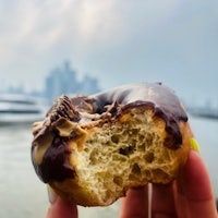 a person holding a donut in front of a city